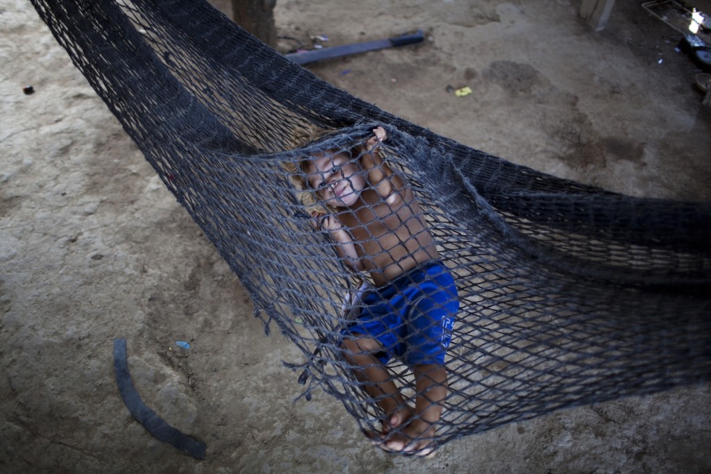 In this May 5, 2012 photo, Gerson Sarai Melgar, 3, rests in a hammock inside his house in "La Confianza" peasant model city, Bajo Aguan, Honduras. Peasants from MUCA (Movimiento Unificado Campesino del Bajo Aguan) occupied around 7000 sq meters of productive land close to the city of Tocoa in the Valley of Bajo Aguan, eastern coast of Honduras in December, 2009. They operate a comercial production of african palm and they also stablished what they call a "peasant model city" called "La Confianza" where more than 300 hundred families live. Since then an open conflict between them and the alleged owner of the land, Miguel Facussé, one of the most powerful businessmen in Honduras has left more than 60 people dead including peasants, security guards, a journalist and members of the Honduran national police. (AP Photo/Rodrigo Abd)