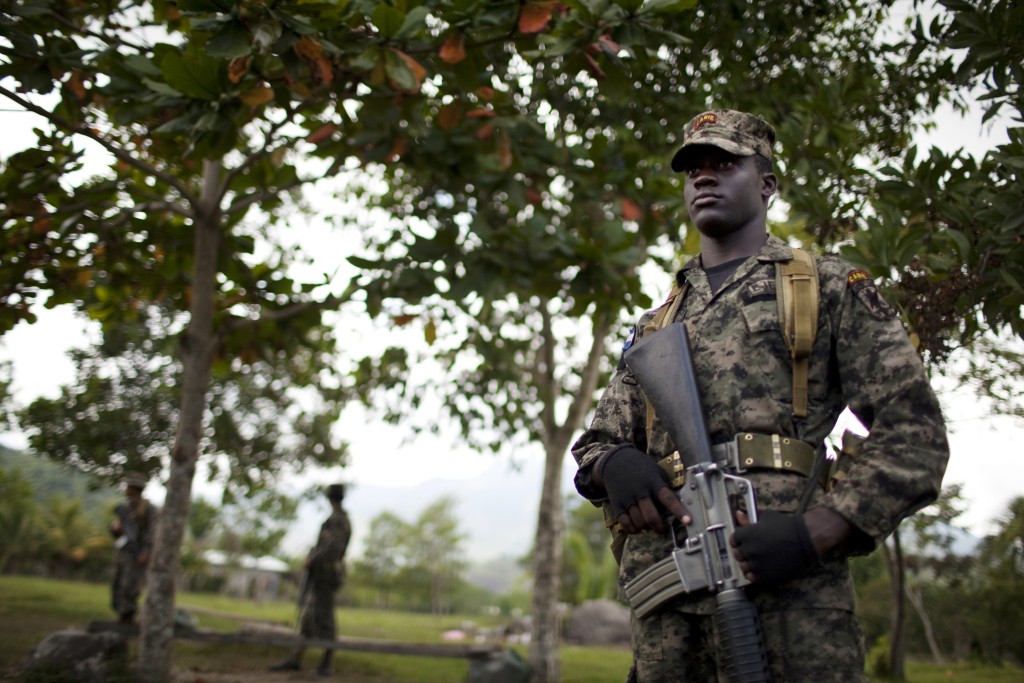 In this May 7, 2012 photo, soldiers stand guard as taking part of the Xatruch military operation in Guadalupe Carmenes, Bajo Aguan, Honduras. Peasants from MUCA (Movimiento Unificado Campesino del Bajo Aguan) occupied around 7000 sq meters of productive land close to the city of Tocoa in the Valley of Bajo Aguan, eastern coast of Honduras in December, 2009. They operate a comercial production of african palm and they also stablished what they call a "peasant model city" called "La Confianza" where more than 300 hundred families live. Since then an open conflict between them and the alleged owner of the land, Miguel Facussé, one of the most powerful businessmen in Honduras has left more than 60 people dead including peasants, security guards, a journalist and members of the Honduran national police. (AP Photo/Rodrigo Abd)