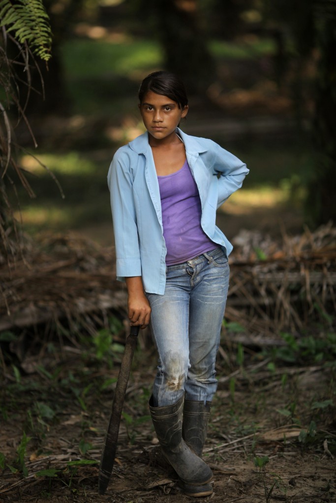In this May 7, 2012 photo, Elsia Acosta, 13, takes a break from cutting grass or "chapeando" the floors of african palm trees in "La Confianza" peasant model city, Bajo Aguan, Honduras. Peasants from MUCA (Movimiento Unificado Campesino del Bajo Aguan) occupied around 7000 sq meters of productive land close to the city of Tocoa in the Valley of Bajo Aguan, eastern coast of Honduras in December, 2009. They operate a comercial production of african palm and they also stablished what they call a "peasant model city" called "La Confianza" where more than 300 hundred families live. Since then an open conflict between them and the alleged owner of the land, Miguel Facussé, one of the most powerful businessmen in Honduras has left more than 60 people dead including peasants, security guards, a journalist and members of the Honduran national police. (AP Photo/Rodrigo Abd)