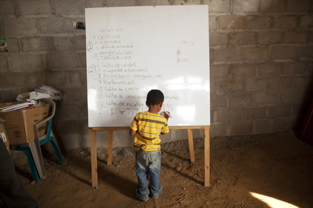 In this May 5, 2012 photo, a boy draws in a blackboard during a class of political formation for the villagers in "La Confianza" peasant model city, Bajo Aguan, Honduras. Peasants from MUCA (Movimiento Unificado Campesino del Bajo Aguan) occupied around 7000 sq meters of productive land close to the city of Tocoa in the Valley of Bajo Aguan, eastern coast of Honduras in December, 2009. They operate a comercial production of african palm and they also stablished what they call a "peasant model city" called "La Confianza" where more than 300 hundred families live. Since then an open conflict between them and the alleged owner of the land, Miguel Facussé, one of the most powerful businessmen in Honduras has left more than 60 people dead including peasants, security guards, a journalist and members of the Honduran national police. (AP Photo/Rodrigo Abd)