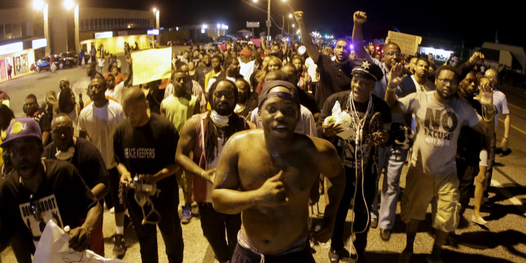 People march Tuesday, Aug. 19, 2014, during a rally for Michael Brown, who was killed by police Aug. 9 in Ferguson, Mo. Brown's shooting has sparked a more than week of protests, riots and looting in the St. Louis suburb. (AP Photo/Charlie Riedel)